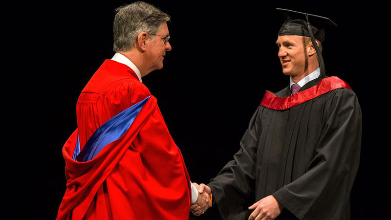 Peter Gill shakes Dean Douglas Miller's hand at convocation 2014