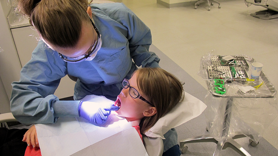 Keanna, a student at St. Maria Goretti Elementary School, is treated by a dentistry student. 