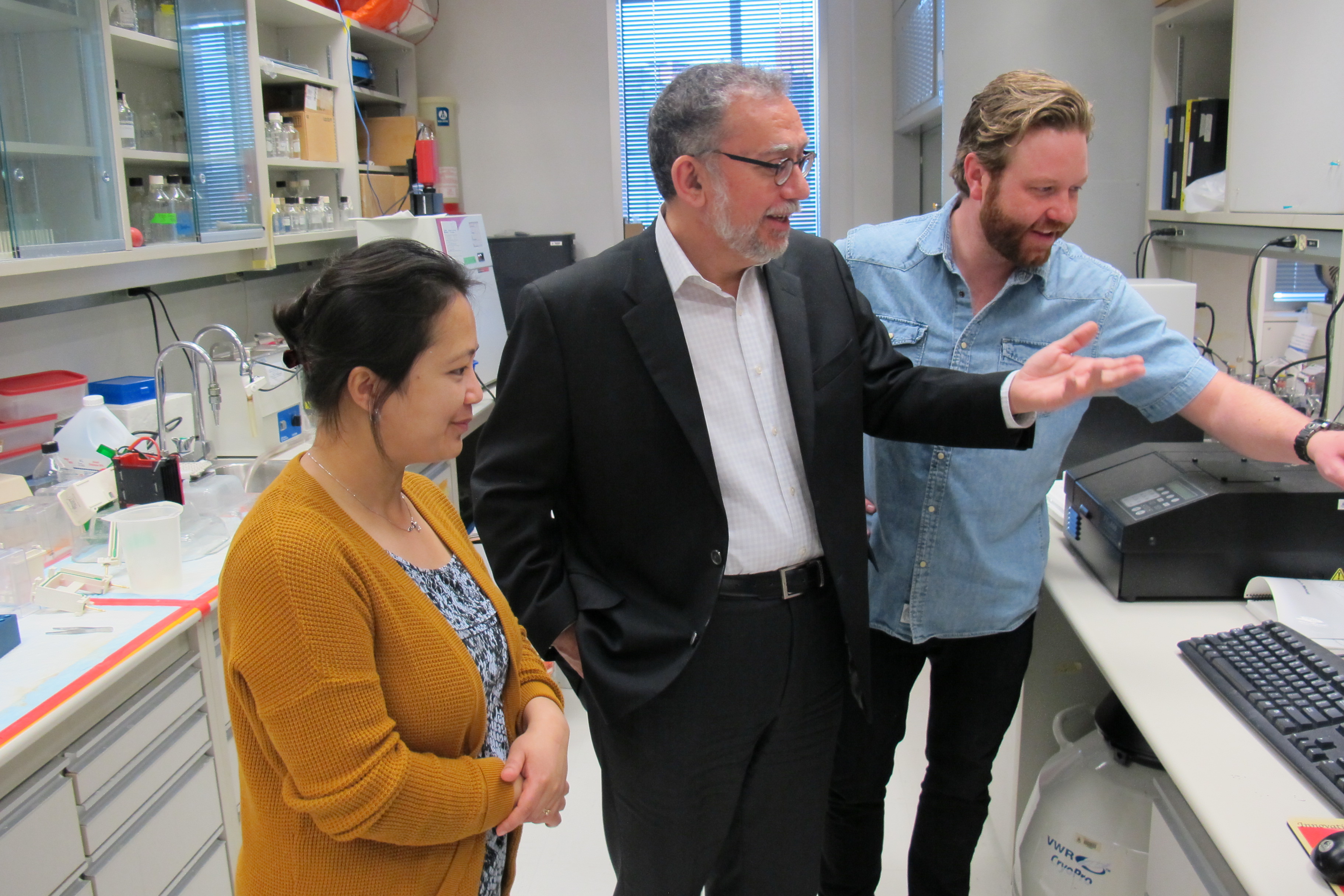 Harissios Vliagoftis speaks with researchers in his lab