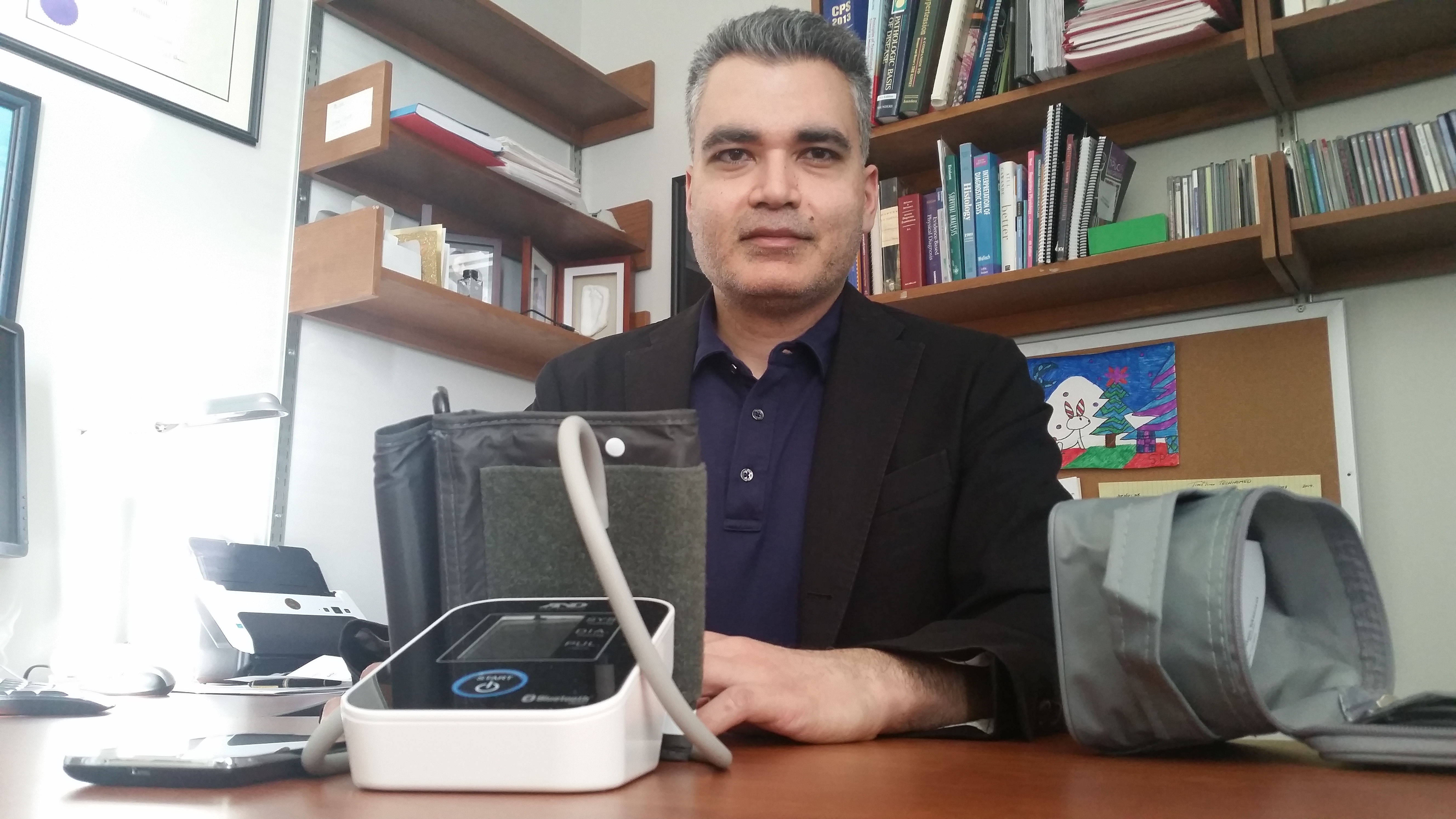 Raj Padwal of the Faculty of Medicine & Dentistry's Division of General Internal Medicine shows equipment to be used for home-based blood pressure monitoring.